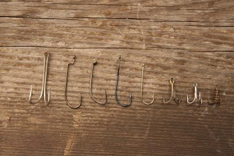 row of several standard fish hooks, some double, some single barbs