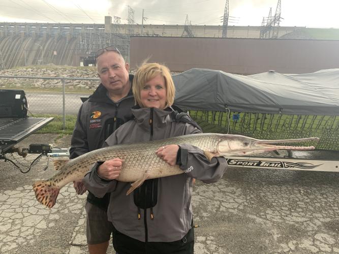 Local fishing guide Cindy Dennison is holding longnose gar with angler Anthony Schnur Jr standing behind her.