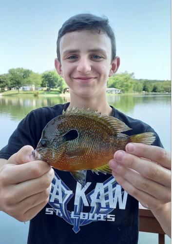 A smiling thirteen year old Robert Audrain IV holds his longear sunfish.