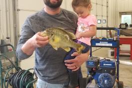 Alex Phillips holds redear sunfish in one hand and young girl in his other arm.